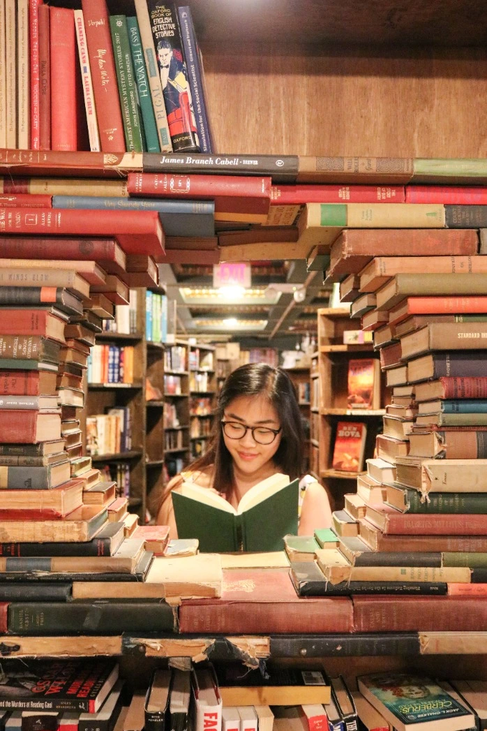Portrait of a girl in a bookstore, amid stacks of books